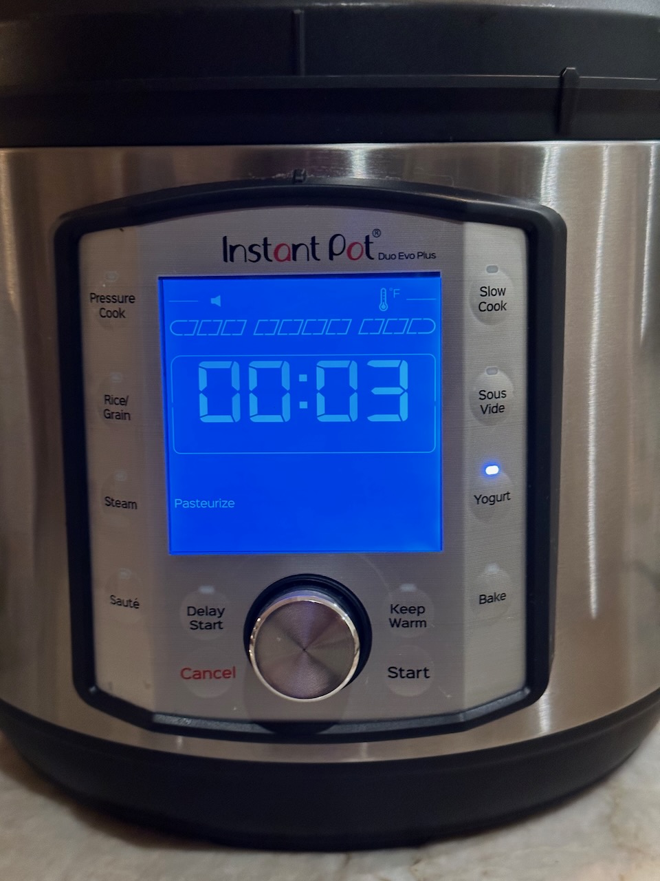 the lit up LCD display of an instant pot, the Yogurt button is illuminated, and the display shows "0:03 Pasteurize"